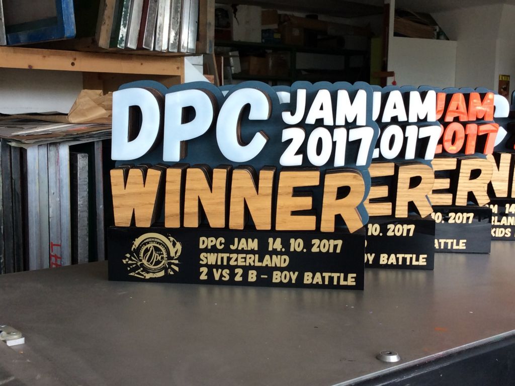Chris Hart GmbH Siebdruck und Beschriftungen Zürich: Fräsarbeiten / Laser cut  - Pokal aus Holz und Plexiglas inkl. goldiger Siebdruck  